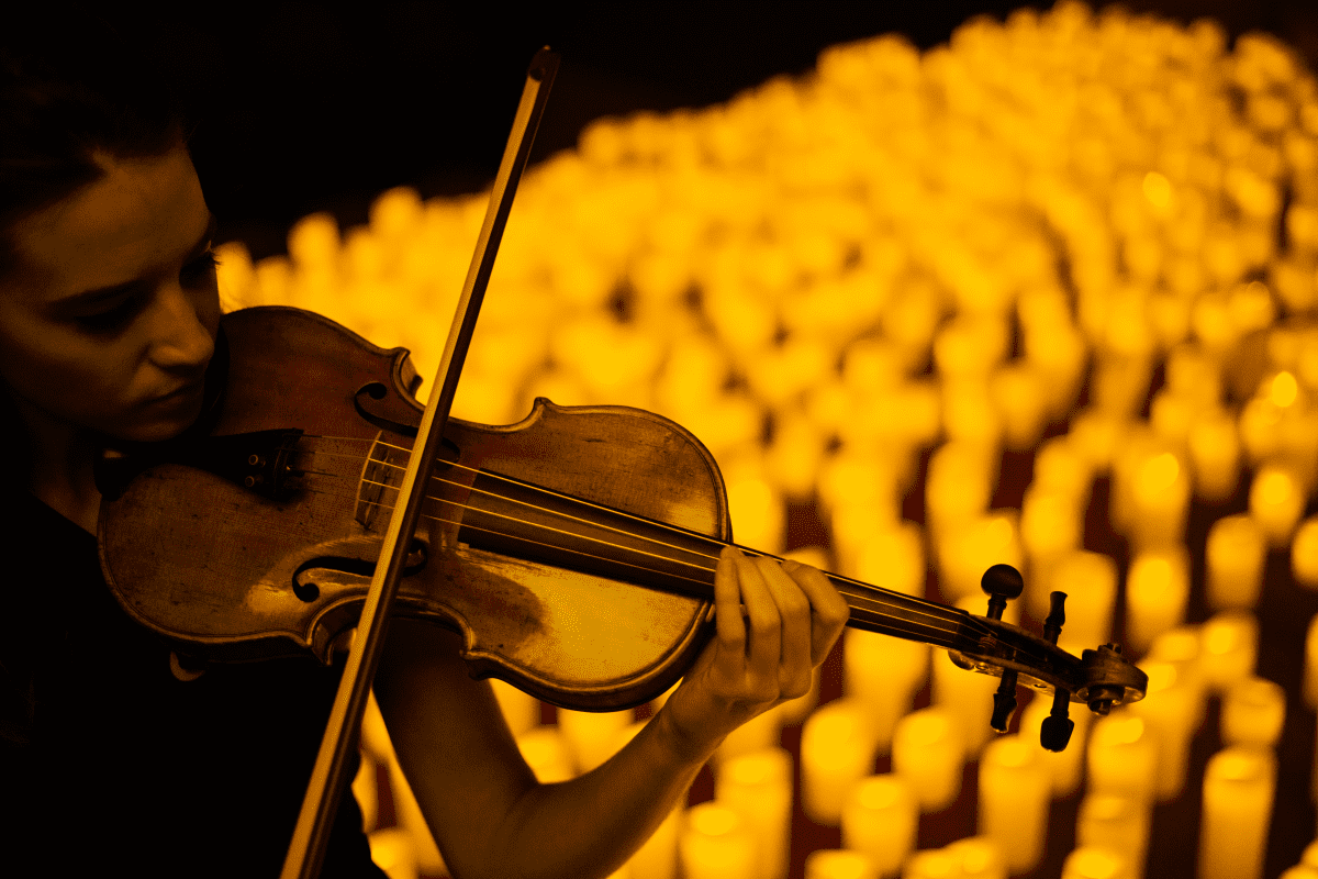 A female violinist playing by candlelight