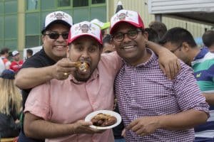 group-of-men-with-wing-fest-hats-on-eating-chicken-wings