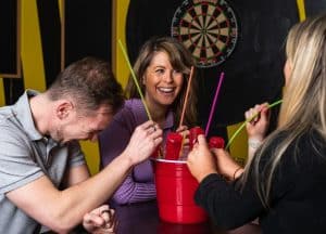 people-at-pong-and-puck-sat-with-cocktail-buckets-and-dart-board-in-background
