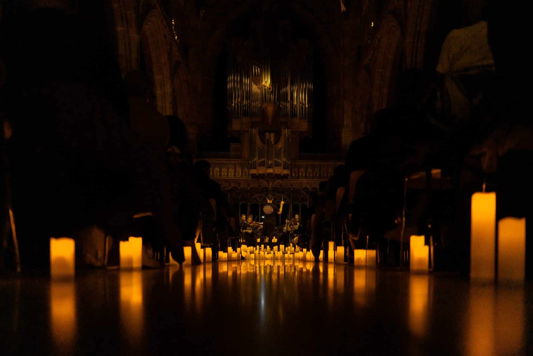 A low image of the aisle at Manchester Cathedral lined by candles.