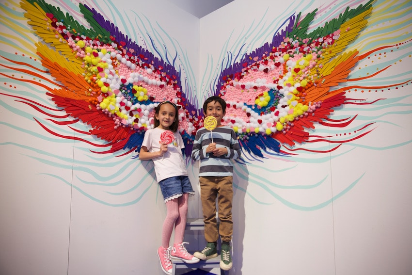 kids with lollies stand in front of wings made from sweets