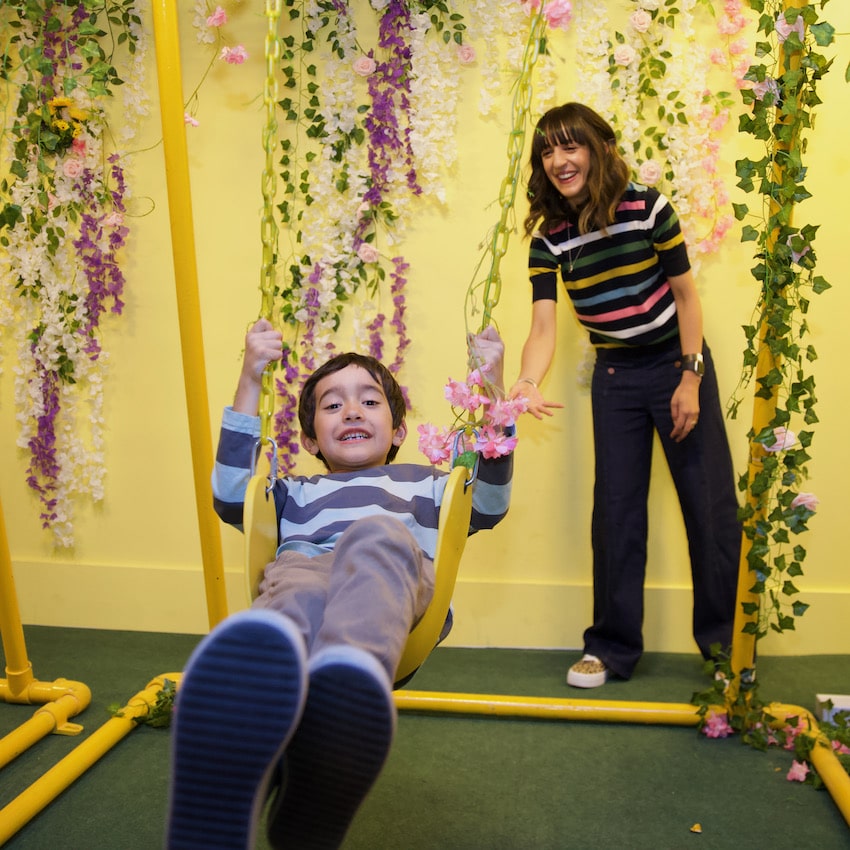 woman pushes bow in swing with floral backdrop