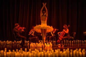a ballerina performs among candlelight in front of a string quartet