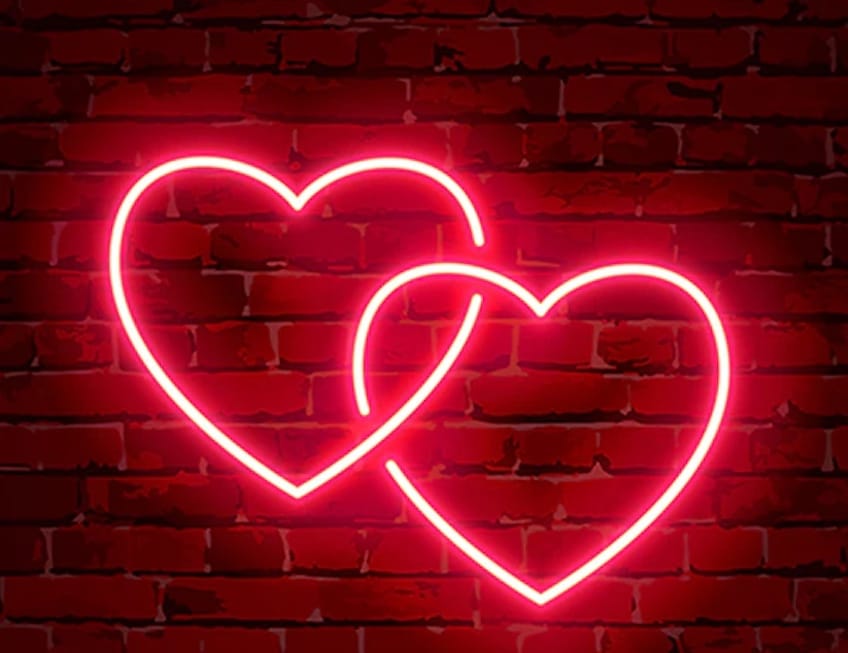 two neon hearts on brick wall