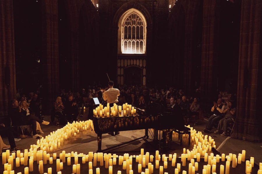 violinist and pianist perform among candlelight in Manchester Cathedral
