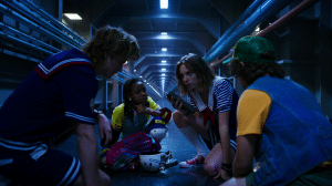 characters from Stranger Things cluster around a walkie talkie