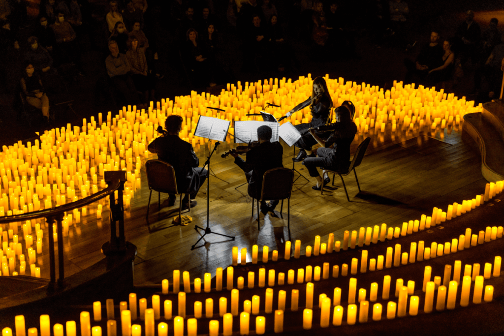 A string quartet performing a Candlelight concert on a stage surrounded by hundreds of candles.
