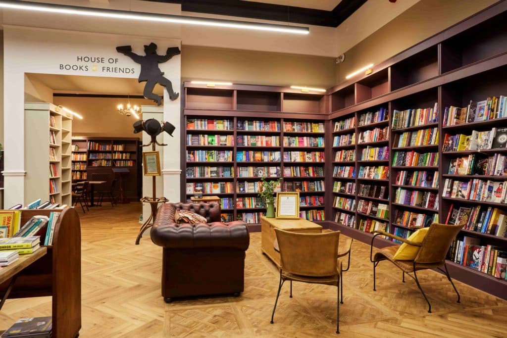 house-of-books-and-friends-manchester-bookshelves-filled-with-books-next-to-two-yellow-chairs-and-a-brown-sofa