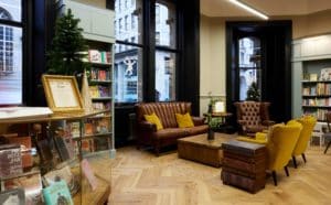 house-of-books-and-friends-manchester-brown-sofas-with-yellow-cushions-on-next-to-windows