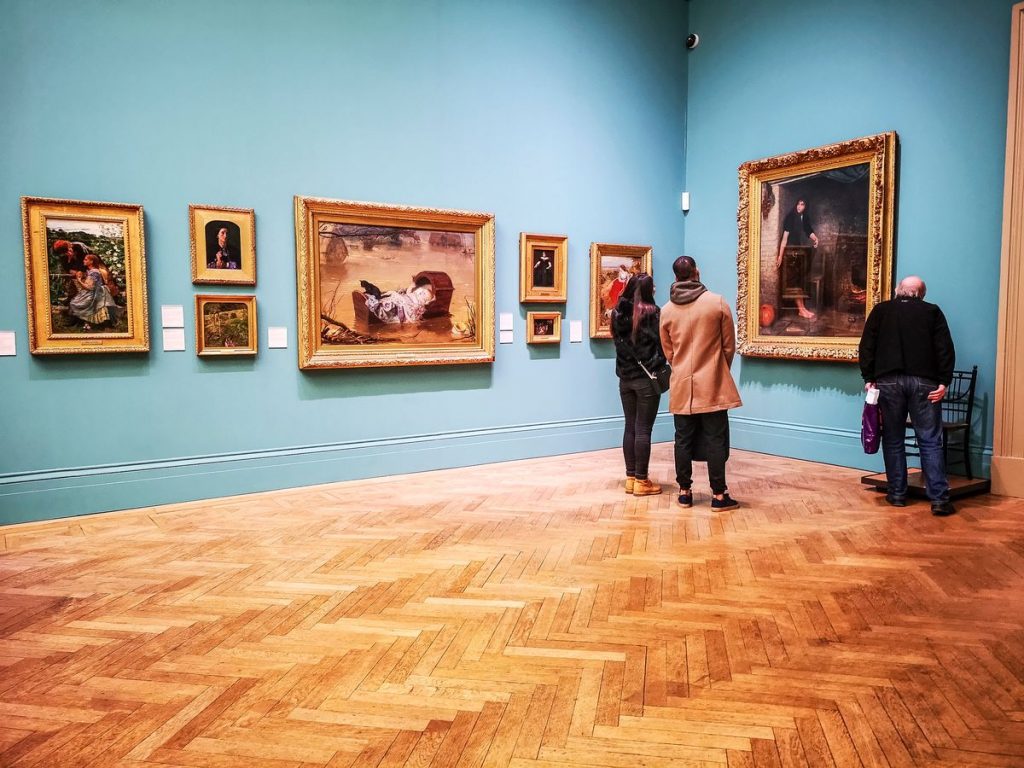 People looking at art on the wall at the Manchester Art Gallery, one of the best of the Manchester art galleries