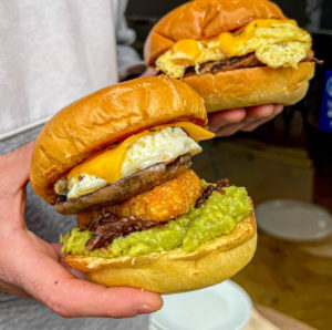 person-holding-two-bold-street-coffee-breakfast-brioche-buns-known-as-buoys