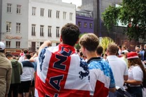 england-fans-in-street-with-england-shirts-and-flags-over-shoulders