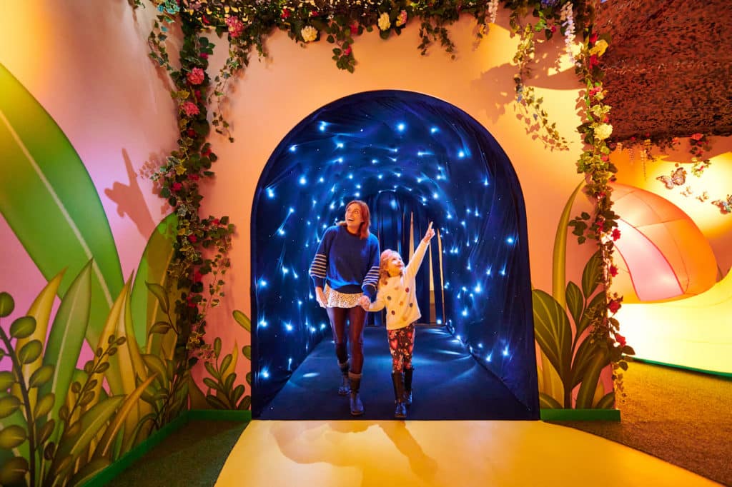 a child and their parent entering Dreamland Imaginarium through a glimmering walkway