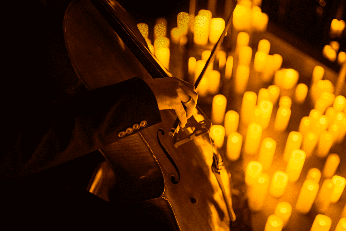 Musician playing a cello surrounded by candles
