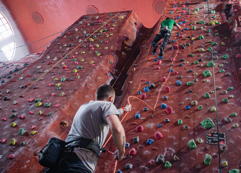 person-belaying-rope-as-person-climbs-rock-climbing-wall-awesome-walls-stockport