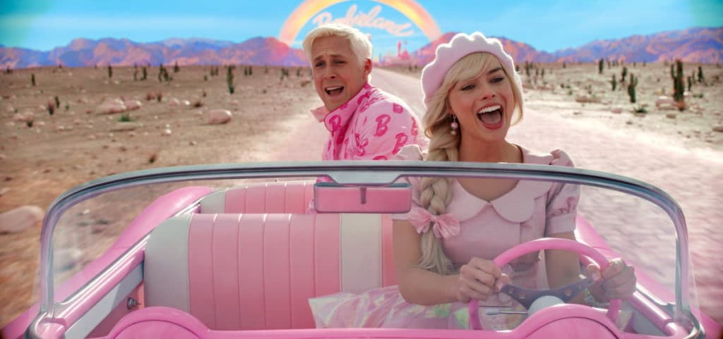 Margot Robbie's Barbie looking happy and Ryan Gosling's Ken looking worried driving in a pink car with a rainbow behind them