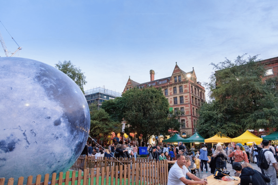 people-sat-outside-at-manchester-moon-festival-2019-with-giant-moon