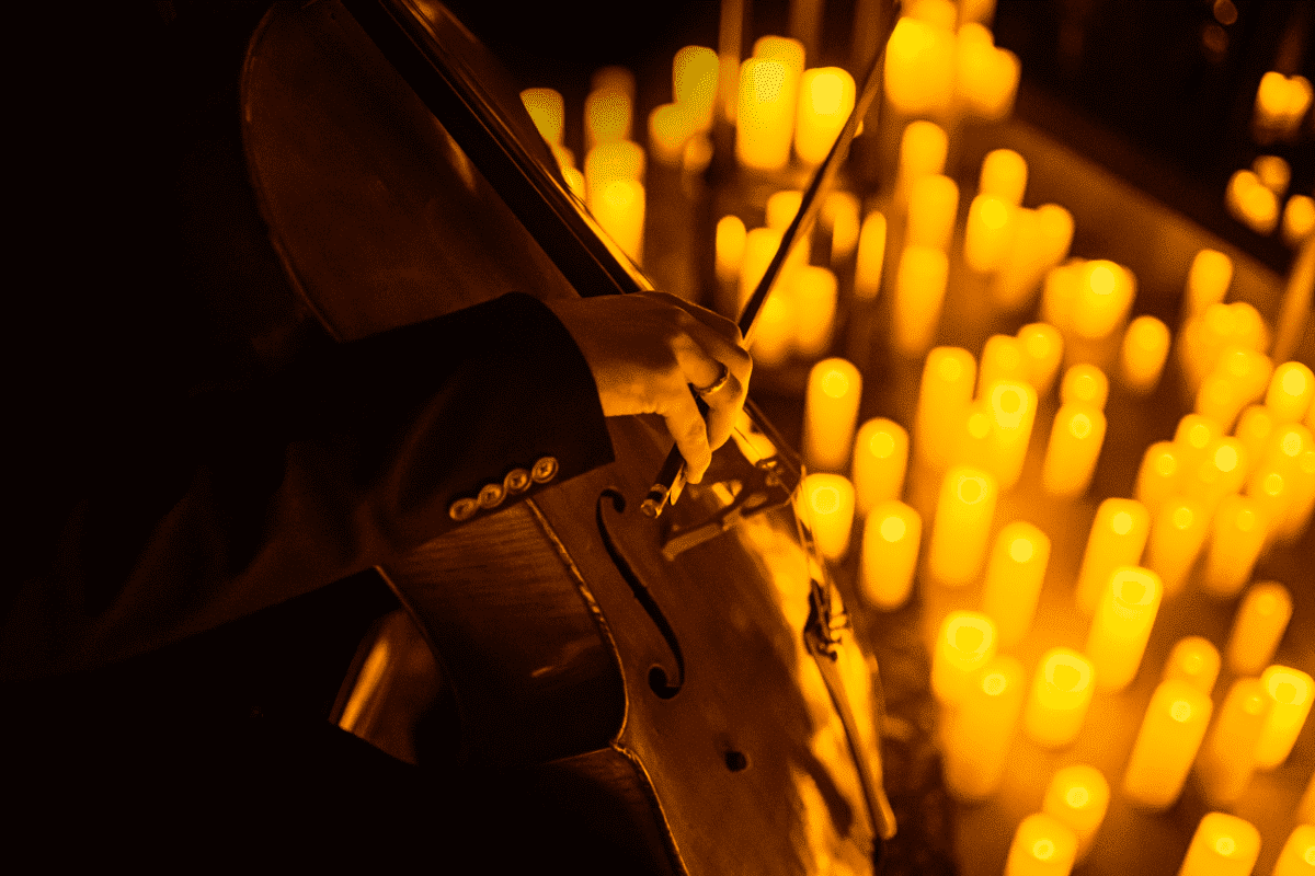 A musician playing a cello by candlelight 