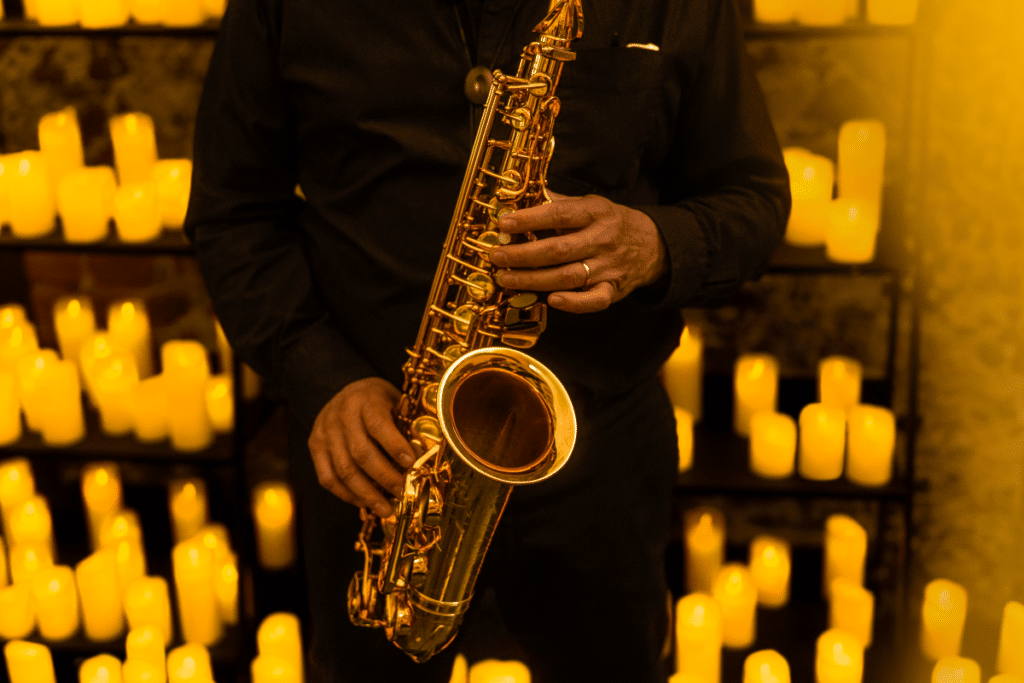 A close up of a musician playing the saxophone with countless candles in the background